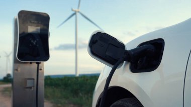 Çevreyi korumak için rüzgar türbininden yeşil ve yenilenebilir enerjiyle çalışan şarj istasyonunda şarj edilen gelişmiş gelecek enerji altyapısı konsepti.
