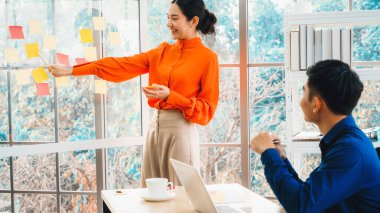 İş adamları ofisteki proje planlama kurulunda çalışıyor ve proje gelişimini analiz etmek için iş arkadaşlarıyla sohbet ediyorlar. Düzenli olması için cama yapıştırılmış yapışkan notlar kullanıyorlar. Jivy