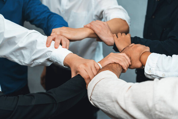 Business team joining hand in circular together symbolize successful group of business partnership and strong collective unity teamwork in community workplace. Prudent
