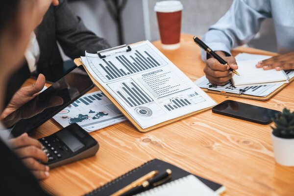 Multiracial analyst team use BI dashboard data to analyze financial report on meeting table. Group of diverse business people utilize data analysis by FIntech for business marketing decision. Concord