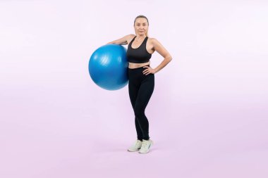 Vücut uzunluğu tam, atletik ve sportif yaşlı bir kadın izole edilmiş arka planda spor topuyla egzersiz yapıyor. Emeklilikten sonra sağlıklı ve aktif bir yaşam tarzı. Etki