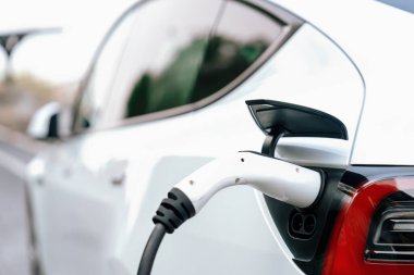 Kapalı EV şarj kolu fişe takıldı veya elektrikli arabaya bağlandı, EV araba aküsünü temiz çevre için sıfır CO2 emisyonu ile alternatif ve sürdürülebilir enerjiyle şarj etti. Kalıcı