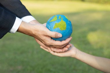 İşadamı, Dünya Günü kavramını, sürdürülebilir gelecek nesiller için daha yeşil çevre korumasına katkıda bulunmak için kurumsal sosyal sorumluluk olarak küçük bir çocuğa Dünya küresi veriyor. Döngü