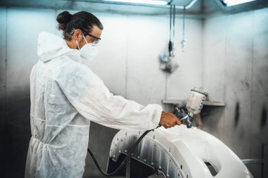 Koruyucu ekipmanlı otomotiv işçisi araba kaportasına sprey tabanca ya da oda atölyesindeki solunum boyasıyla renk boyası uyguluyor. Tamir için araba boyama servisi. Oxus.