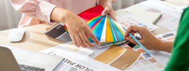 Profesyonel iç mimarların kırpılmış görüntüleri renk paletinden uygun renkler seçiyor ve ev modeli ve mimari ekipmanlar etrafa saçılıyor. - Yakın çekim. Eline odaklan. Değiştirilmiş.