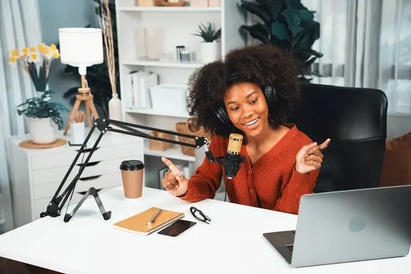 Host channel of beautiful African woman talking in online broadcast teaching marketing influencer, with listeners in broadcast or online. Concept of anywhere at work place. Tastemaker.