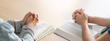 İki inanan kutsal kitap üzerinde ahşap kiliseye ahşap haçla birlikte dua ediyorlar. Umut, din, inanç, Hıristiyanlık ve Tanrı 'nın kutsaması kavramı. Yüzü dönük el. Filizlenen.