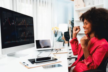 Afrikalı kadın blogcu güler yüzlü, yüksek kârla değer verilen borsa başarısıyla ekrana bakıyor. Bilgisayarda ticaret uygulamasında döviz yatırımı kavramı. Tatlandırıcı.