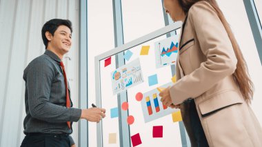 İş adamları ofisteki proje planlama kurulunda çalışıyor ve proje gelişimini analiz etmek için iş arkadaşlarıyla sohbet ediyorlar. Düzenli olması için cama yapıştırılmış yapışkan notlar kullanıyorlar. Jivy