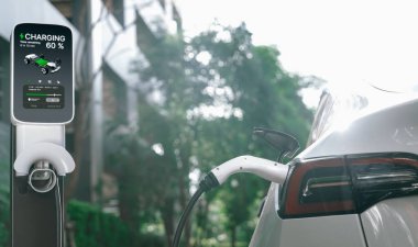 Yazın yeşil sürdürülebilir şehir bahçesinde elektrikli araba şarj oluyor. Kentsel sürdürülebilirlik yaşam tarzı yeşil temiz yeniden şarj edilebilir enerji elektrikli BEV araç iç organları