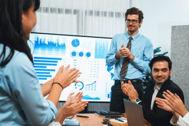 Kutlama jesti ve başarılı takım çalışması yapan bir grup mutlu çoklu etnik iş adamı başarılı satışlar yaptıktan sonra veya toplantı odasında ekranda pozitif finansal veri gösterimi yaptıktan sonra. Habiliment