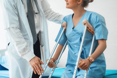 Doktor hastanede koltuk değnekli hastayla ilgileniyor. Fizyoterapist ve bacak yaralanması konsepti. Jivy