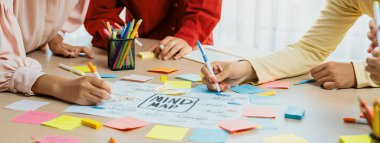 Yaratıcı iş adamları, zihin haritalama kullanarak pazarlama stratejisi ve iş planı hakkında beyin fırtınası yapıyorlar. Girişim ekibi kağıda yazmak için birlikte çalışır. Eline odaklan. - Yakın çekim. Değiştirilmiş.