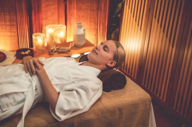 Beyaz kadın müşteri stres önleyici spa masajının keyfini çıkarıyor ve lüks otel ya da otelde sıcak mum ışığında güzellik teniyle eğleniyor. Sessiz.