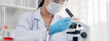 Laboratuvar araştırmacısı mikroskop kullanarak yeni ilaç ya da tedavi geliştirir. Laboratuvar mikrobiyoloji ekipmanları ile bilimsel uzmanlık ile sağlık hizmetlerinin teknolojik gelişimi. Panorama Katı