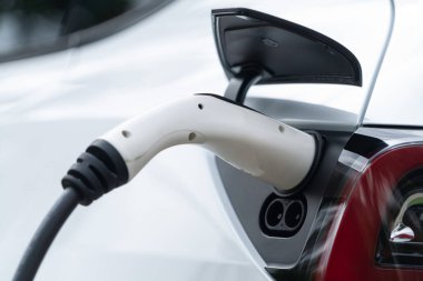 Elektrikli araç portuna bağlı EV şarj prizi kolu şarj istasyonundan şarj oluyor. Modern tasarlanmış EV araba ve daha iyi bir gelecek konsepti için temiz enerji sürdürülebilirliği. Eşzamanlama