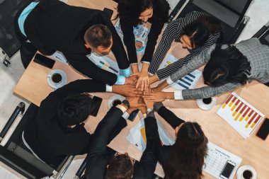 Mutlu iş adamları takım çalışmasının başarısını kutlarken ofis masasında yukarıdan çekilen neşeyle kutluyorlar. Genç işadamı ve işkadını işçiler, neşeli zafer gösterisi birliği desteği gösterdiler. Jivy