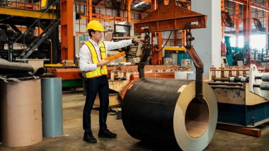 Makine operatörü çelik üretim makinelerini ustalıkla çalıştırıyor, metal fabrikasındaki ağır inşaat mühendisliği malzemeleri için silindir rulo çelik üretiyor. Örnek gösteriliyor