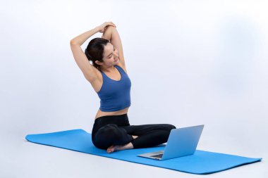 İnternetteki videodan alınan talimatlara göre spor kıyafeti giymiş genç Asyalı bir kadın spor egzersizinden önce geriniyor. Sağlıklı atletik bir kadınla vücut egzersizi izole bir zeminde ısınıyor. Kuvvetli