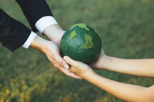 Businessman hand giving Earth globe to little boy as Earth day concept as corporate social responsible to contribute greener environmental protection for sustainable future generation. Gyre