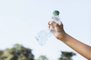 Geri dönüşümlü plastik şişe gökyüzü arka planında el ele tutulur. Geri dönüşüm için plastik atık bulundurmak etkili geri dönüşüm yönetimi ile temiz çevreyi desteklemek için konsepti azaltmak ve yeniden kullanmak. Döngü