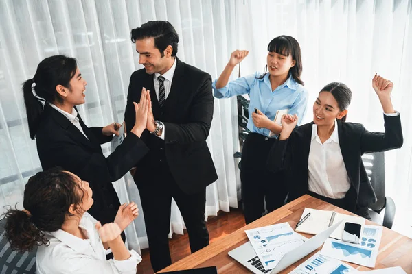 Group of happy businesspeople in high five gesture and successful efficient teamwork. Diverse race office worker celebrate after made progress on marketing planning in corporate office. Meticulous