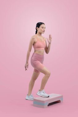 Çalışkan, enerjik bir kadın atölyede egzersiz yapıyor. Kardiyo aerobik hareketleriyle izole bir arka plan. Genç atletik Asyalı kadın mahareti ve dayanıklılık eğitimi konsepti.