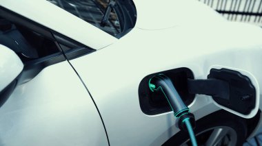 Otoparkta şarj edilen EV şarjlı elektrikli araba. Alternatif temiz ve sürdürülebilir enerji kullanan geleceğin yenilikçi yenilenebilir EV arabası. İnceleyin