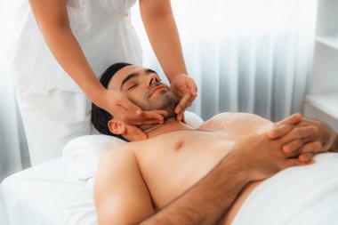 Beyaz adam stres önleyici kafa masajından ve lüks bir tatil beldesi veya otel spa salonundaki modern ışık ortamında yüz güzelliği eğlencelerini şımartmaktan hoşlanıyor. Sessiz.