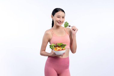 Spor giyim mağazasında elinde meyve ve sebze dolu salata kasesi tutan genç bir Asyalı kadın. Doğal gençlik ve uygun vücut yaşam tarzı izole edilmiş arka planda dengeli beslenme. Kuvvetli