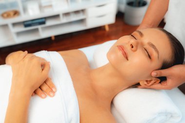 Kafkasyalı kadın stres önleyici kafa masajından ve lüks tatil beldesi ya da otel spa salonundaki modern ışık ortamında yüz güzelliği eğlencelerini şımartmaktan hoşlanıyor. Sessiz.