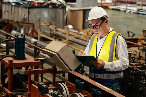 Fabrika mühendisi endüstriyel çelik oluşum makinesini teftiş ediyor. Metal makine mühendisliği denetim denetçisi olarak liderliği gösteriyor..