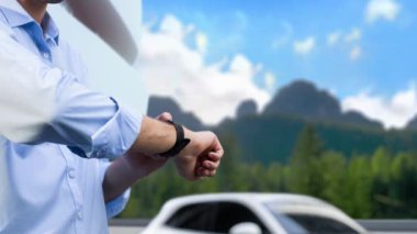 İş adamı, doğal arka planda çevre dostu elektrikli araba kullanarak şarj istasyonundan, tatilden ve seyahatten hologramda EV 'nin dijital batarya durumunu kontrol ediyor. İnceleyin