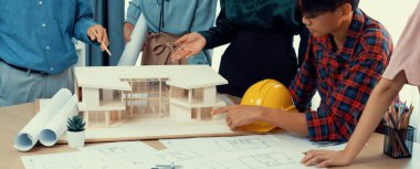Mimari takım analizi ve ev modeli, plan ve mimari ekipmanlarla toplantı masasında ev inşaatı hakkında beyin fırtınası. Yaratıcı tasarım ve takım çalışması. Filizlenen.