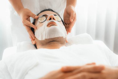 Kaplıca salonunun sakin atmosferi, insan müşterisi lüks salatalıklı yüz maskesi ile kendini yenileme zevkine kapılıyor. Yüz bakımı tedavisi ve güzellik konsepti. Sessiz.