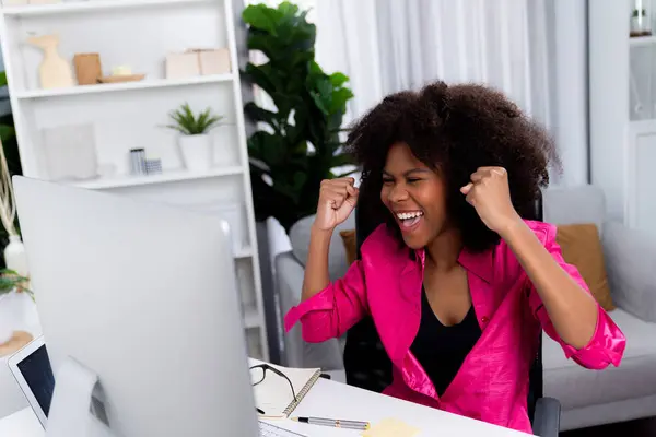 African woman blogger extremely happy face, looking on screen with valued achievement at high profit with newest company project. Concept of cheerful expression work from home lifestyles. Tastemaker.