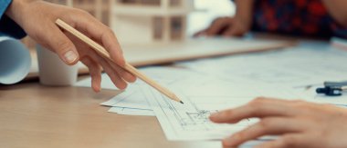 Meslektaşım ev inşaatını ölçüp incelerken kalem kullanarak projeye işaret eden profesyonel mimar el yapımı bir resim. Yaratıcı tasarım ve takım çalışması konsepti. Filizlenen.