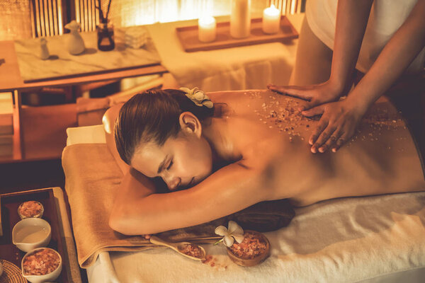 Женщина-клиент, проводящая пилинг в роскошном спа-салоне с теплым свечой окружающей среды. Косметическое лечение бальзамическим скрабом в Health spa scrub. Quiescent