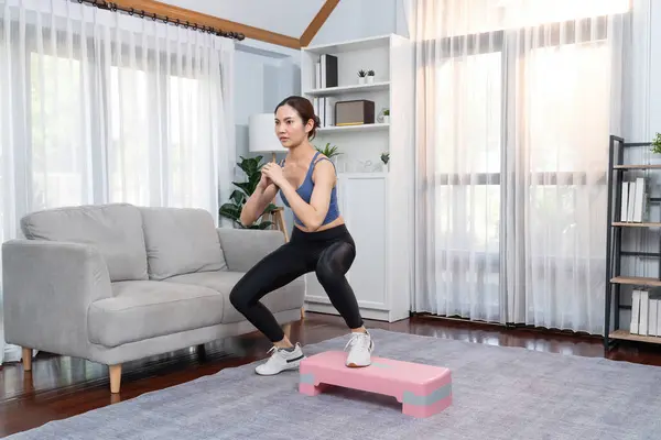 Vigorous energetic woman doing exercise at home, cardio aerobic step workout. Young athletic asian woman dexterity and endurance training session as home workout routine concept.