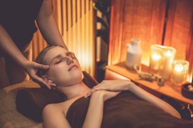 Beyaz kadın stres önleyici kafa masajı yapmaktan ve lüks otel veya otelde sıcak mum ışığında yüz güzelliği eğlencesi yapmaktan zevk alıyor. Sessiz.