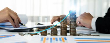 Dijital grafik göstergeli bozuk para yığını iş yatırımını ve ekonomik büyümeyi sembolize ediyor. Finansal hedefe ulaşmak ve kâr sağlamak için finansal planlama yapan bir iş adamı. Kurnaz.