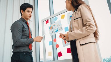 İş adamları ofisteki proje planlama kurulunda çalışıyor ve proje gelişimini analiz etmek için iş arkadaşlarıyla sohbet ediyorlar. Düzenli olması için cama yapıştırılmış yapışkan notlar kullanıyorlar. Jivy