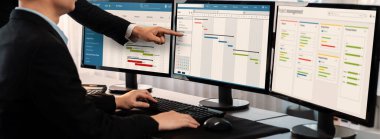 Projeyi koordine eden ve güncelleyen proje ekibi Gantt çizelge yazılımını kullanarak bilgisayarda program planladılar. Şirket işi için zaman ve süre belirleyen iş adamları. Önde.