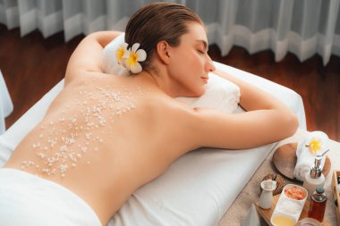 Lüks spa salonlarında sıcak mum ışığında cilt bakımı yaptıran kadın müşteri. Sağlık Spa vücut fırçasında tuz temizleme güzellik tedavisi. Sessiz.