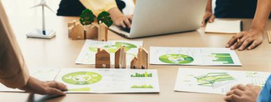 Yeşil şehri temsil eden tahta blok ve yenilenebilir enerji temsil eden rüzgar değirmeni çevresel belgelerle birlikte yeşil iş toplantısının merkezine yerleştirildi. Yeşil iş konsepti. Tanımlama.