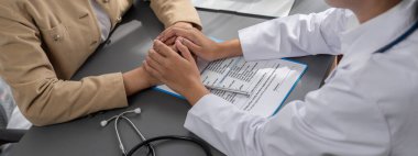 Doktor, doktor kliniğinde destekleyici ve profesyonel olduğu için genç hasta elini tutarken tıbbi teşhis raporunu ve şefkatli bir sağlık hizmeti danışmanlığı sunduğunu göster. Neoterik