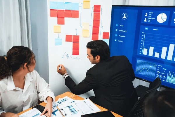 Stock image Diverse group of business analyst team analyzing financial data report. Finance data analysis chart and graph dashboard show on TV screen in meeting room for strategic marketing planning. Habiliment