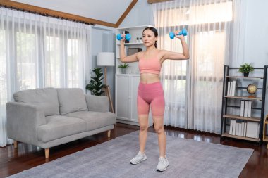 Güçlü enerjik kadın evde halter kaldırma egzersiziyle yoga yapıyor. Genç atletik Asyalı kadın dayanıklılığı ve dayanıklılık antrenmanı. Ev ödevi olarak..