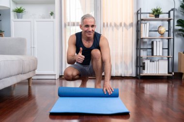 Aktif ve sportif son sınıf öğrencisi evdeki oturma odasında spor paspası hazırlıyor. Emeklilikten sonra sağlıklı yaşam biçimi konsepti olarak ev egzersizi. Etki