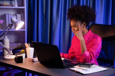 Ciddi yüzlü pembe tişört giyen Afrikalı kadın iş kadını ya da blog yazarı, mücadele projeli ekran laptopuna bakıyor ve odaklanıyor. Evdeki stresli ifade anlayışı. Tatlandırıcı.